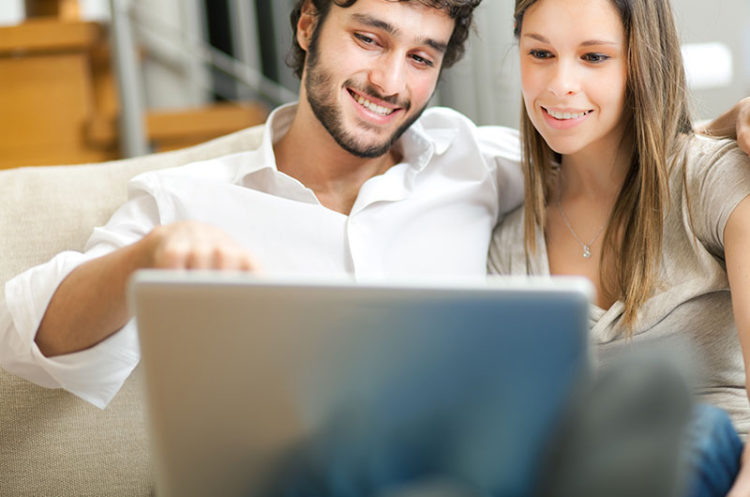 A man and woman looking at the screen of their laptop.